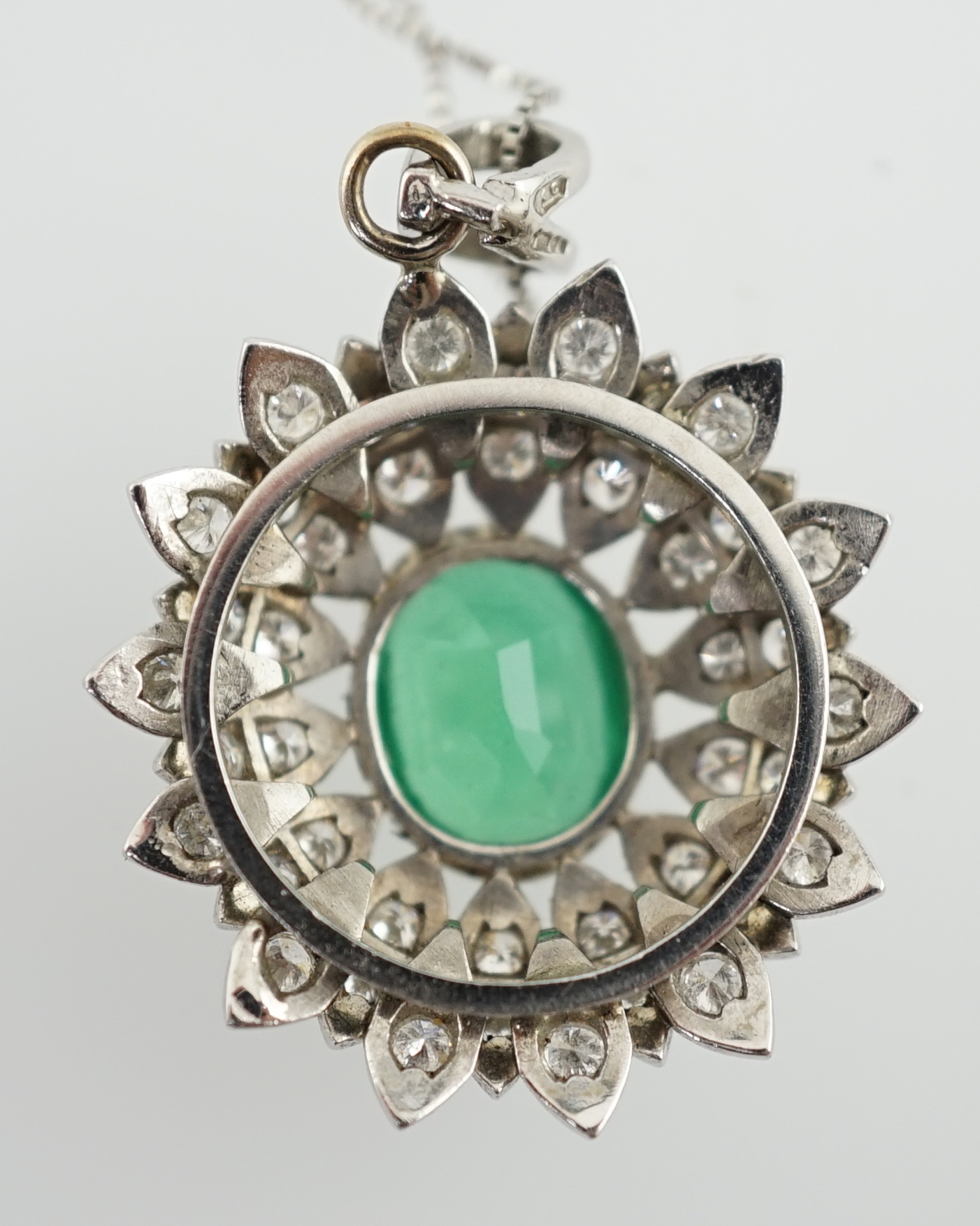 A modern platinum, emerald and diamond cluster set oval pendant